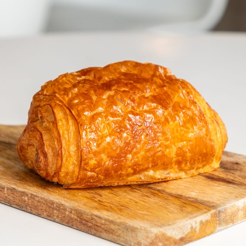 Golden-brown pain au chocolat pastry on a rustic wooden cutting board.